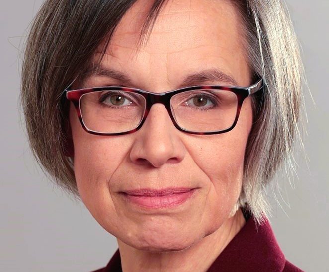Brigitte Hövel, Frau mit grauen Haaren, Brille und freundlichem Gesichtsausdruck. Heller Hintergrund